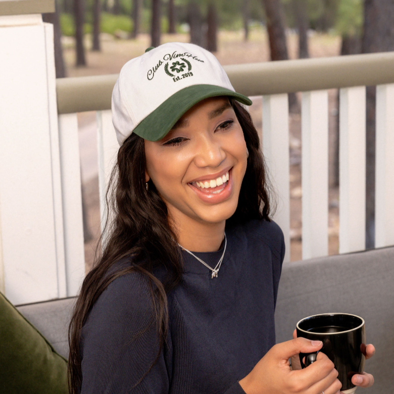 Woman wearing a cap and holding a mug outdoors